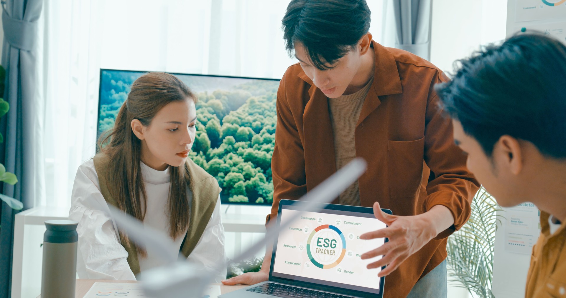 Team members examine ESG-related documents, pointing and discussing investment strategies for sustainable and renewable energy resources. Eco-Friendly Business Team Discussing ESG Goals.